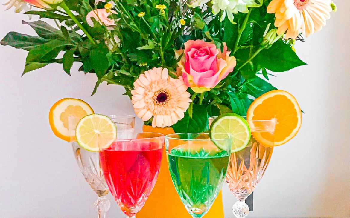Värikkäät alkoholittomat juomat ja kukkakimppu